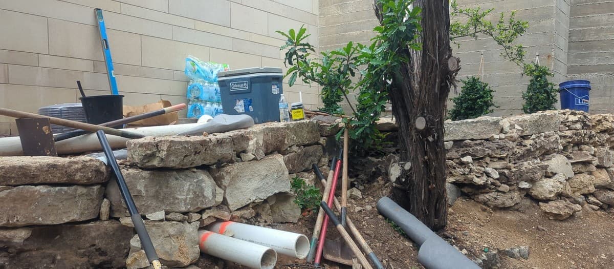 Freestanding garden wall built without mortar — dry-stack block technique, batter, and coping detail
