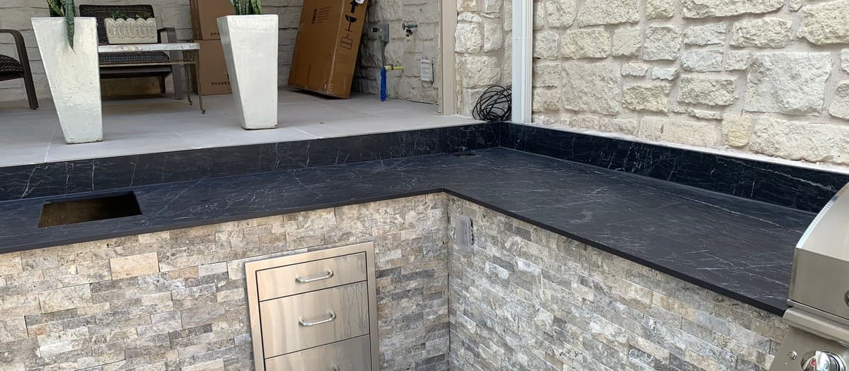 Complete outdoor kitchen installation — masonry base, appliance placement, gas line, and countertop detail