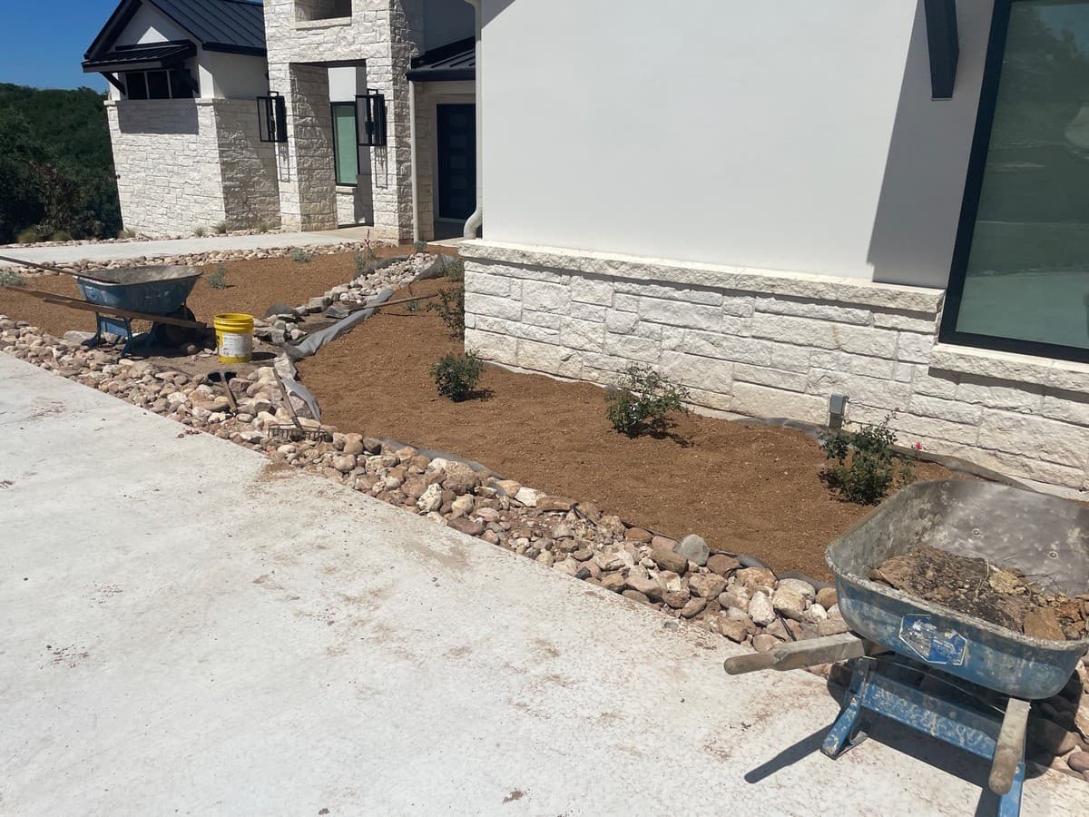 Dry creek bed construction cross-section showing filter fabric, drainage gravel, and decorative stone layer