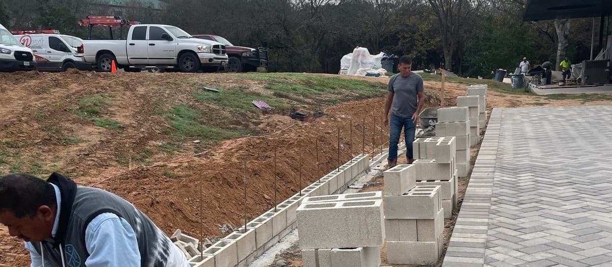 Hardscape crew compacting base for paver installation — production rate estimation for landscape contractors