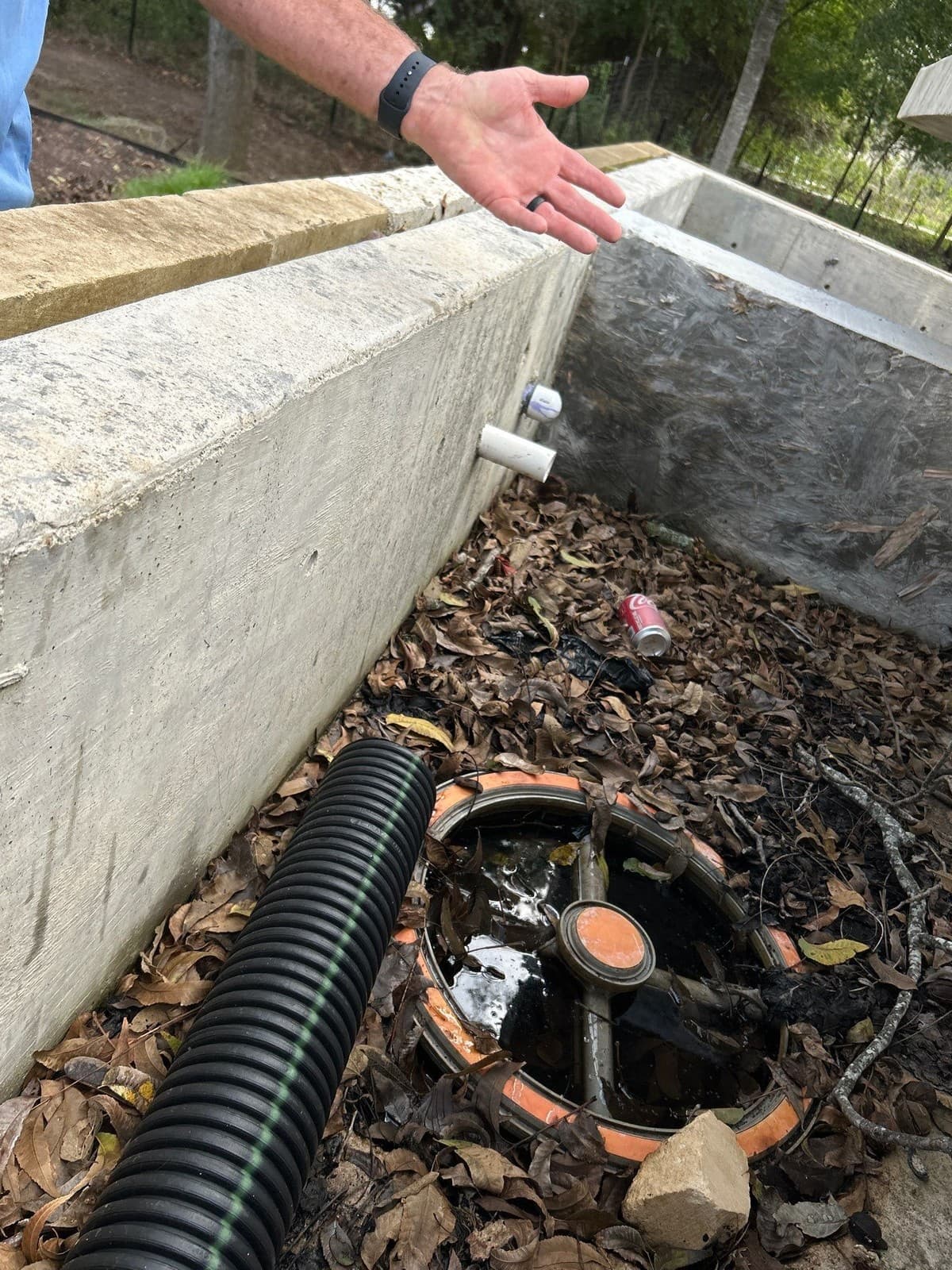 French drain cross-section showing 1% minimum slope, perforated pipe orientation, and gravel surround depth