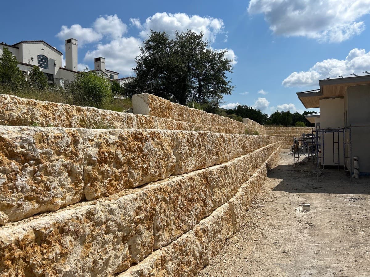 Retaining wall material comparison showing natural limestone vs segmental block for residential landscape