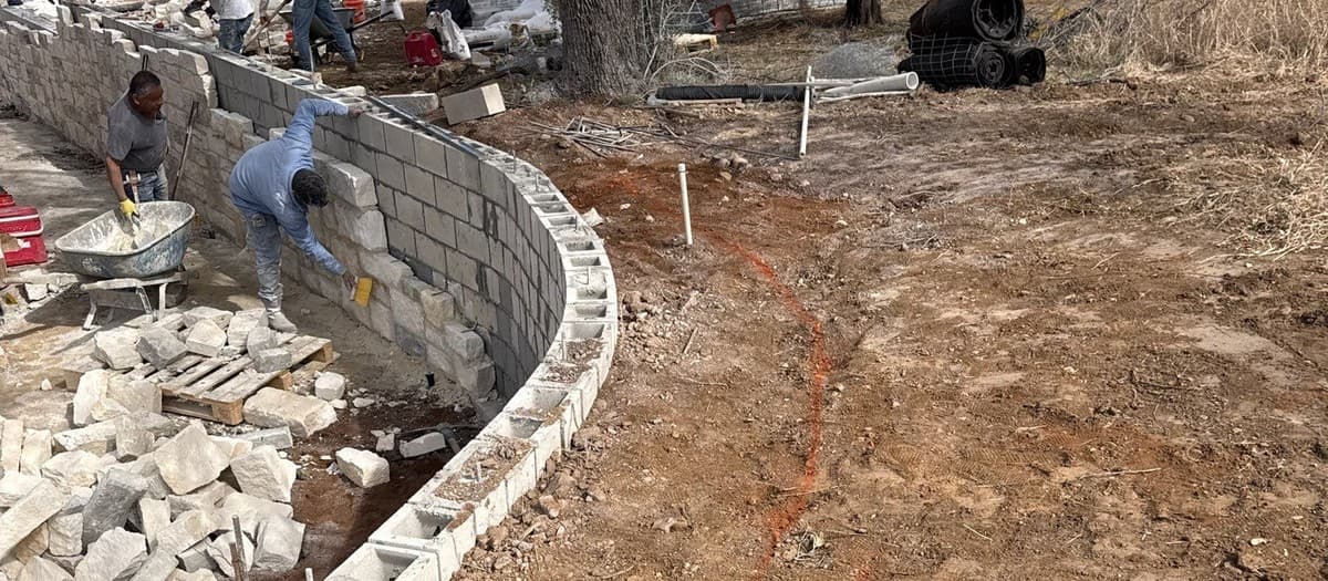 Natural stone vs concrete block retaining wall comparison — cost, appearance, drainage, and installation