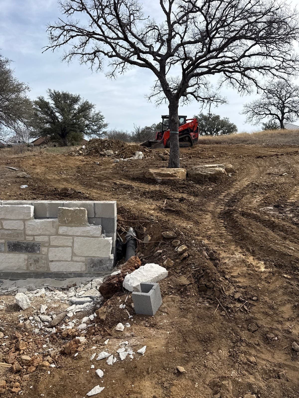 Retaining wall installation cross-section showing compacted base, first course setting, batter, and drainage pipe
