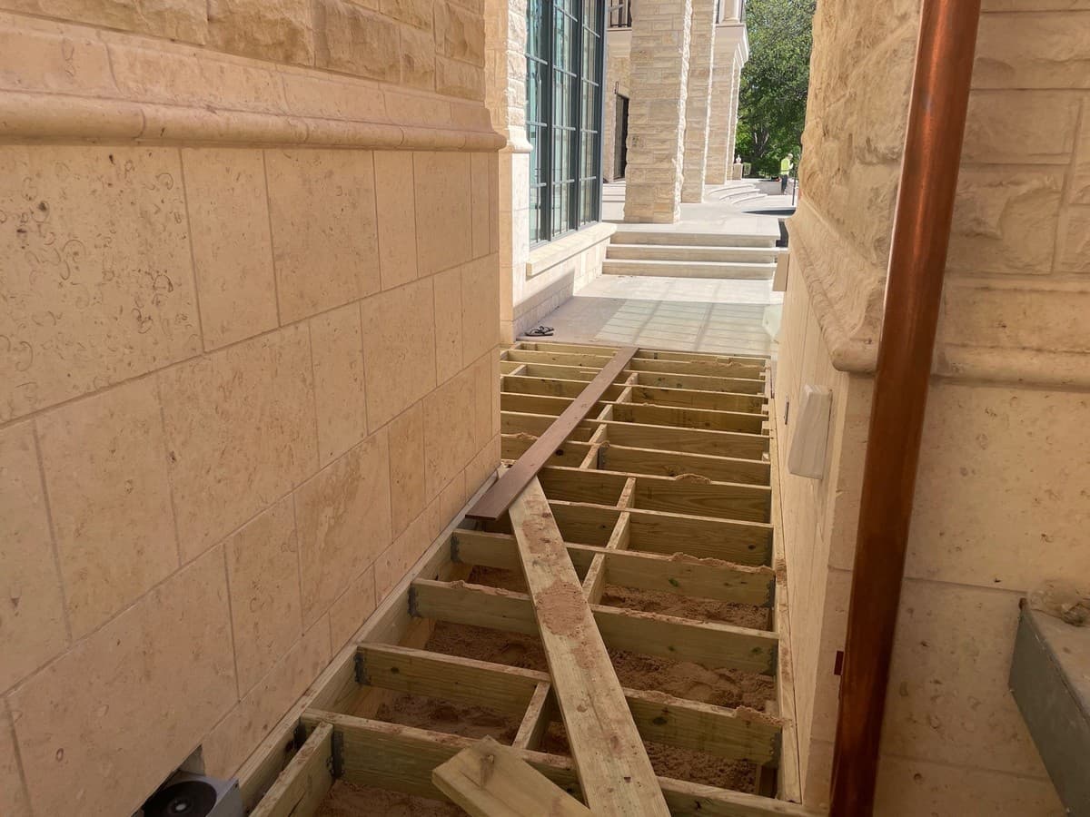 Deck framing detail showing footing depth, post base, beam, joist hanger, and ledger flashing installation